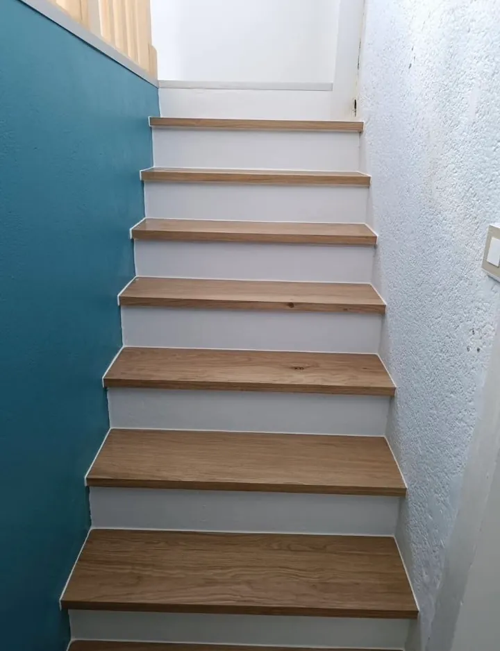 Escalier avec marches en chêne et contremarches blanches, mur bleu canard