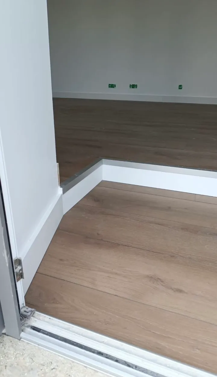 Pose de parquet stratifié avec plinthes blanches dans une pièce en rénovation