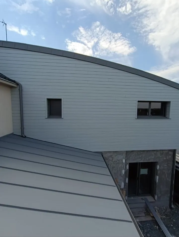 Bardage gris et toiture courbe d'un bâtiment vus en hauteur