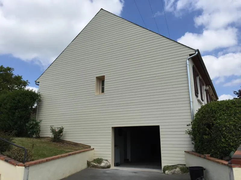 Bardage PVC beige posé sur le pignon d'une extension de maison