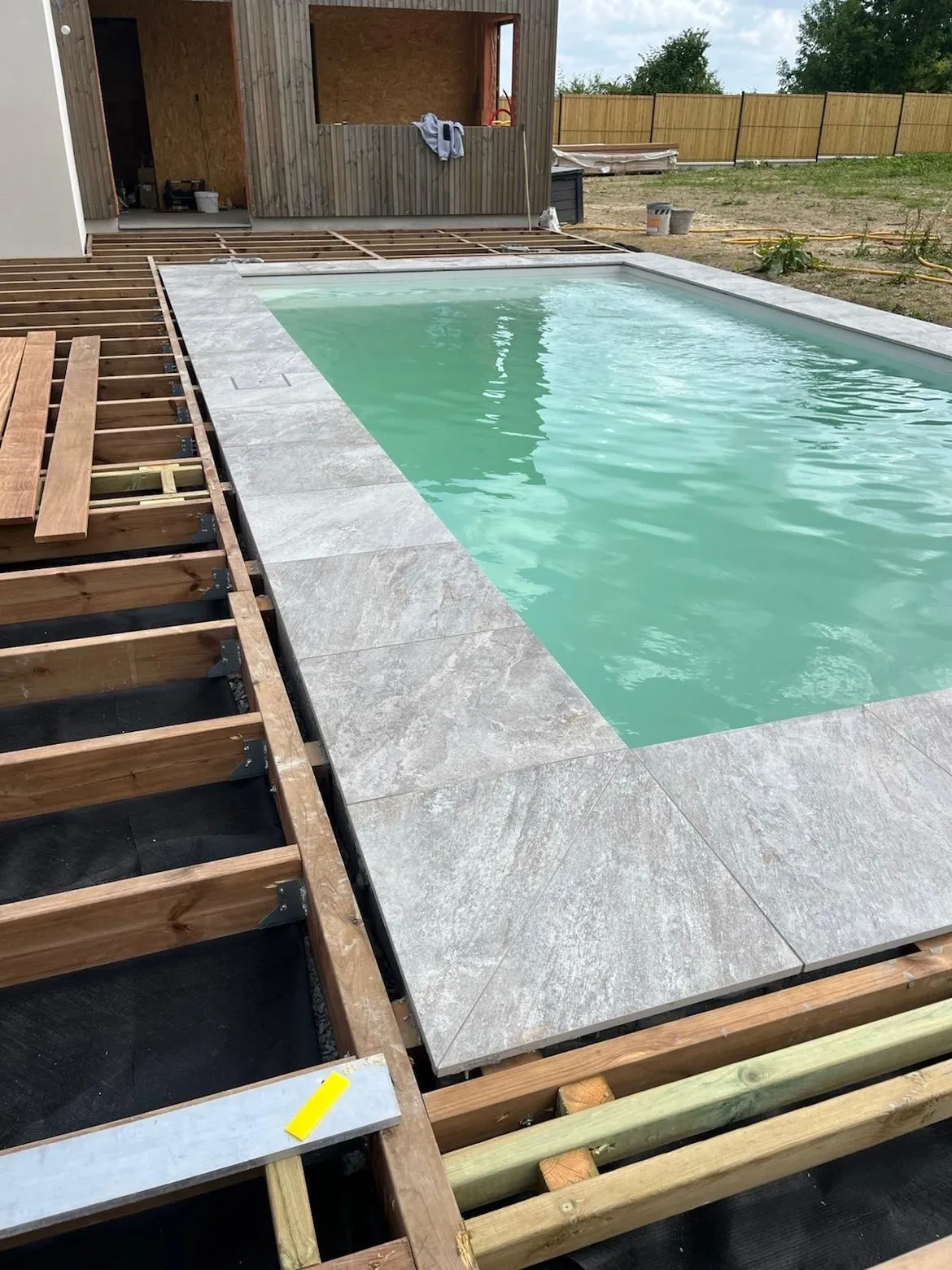Pose de carrelage sur une terrasse de piscine en cours de construction avec ossature bois