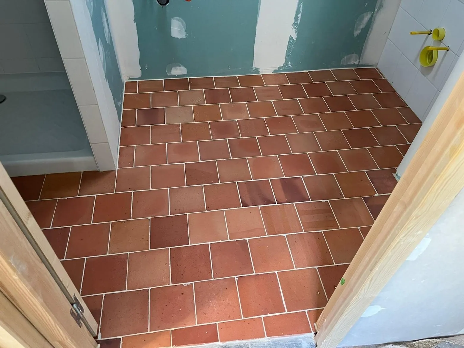 Carrelage terre cuite posé au sol d'un couloir menant à une salle de bain