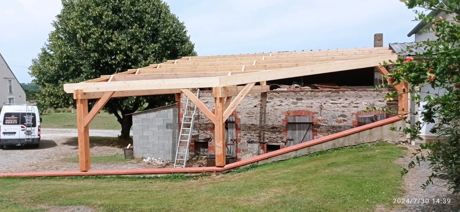 Charpente bois d'un carport ouvert adossé à un mur en pierre