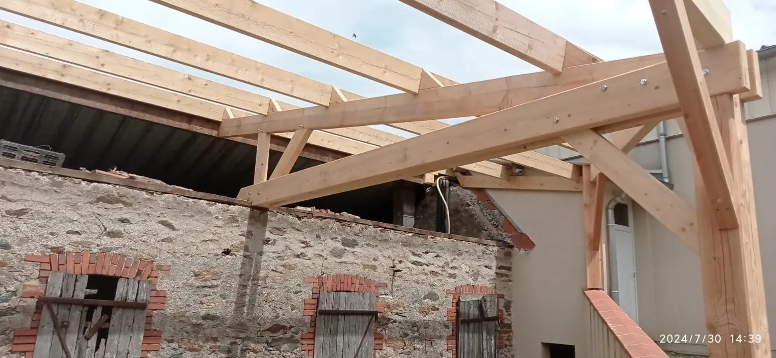 Charpente bois posée en extension sur un mur en pierre ancien