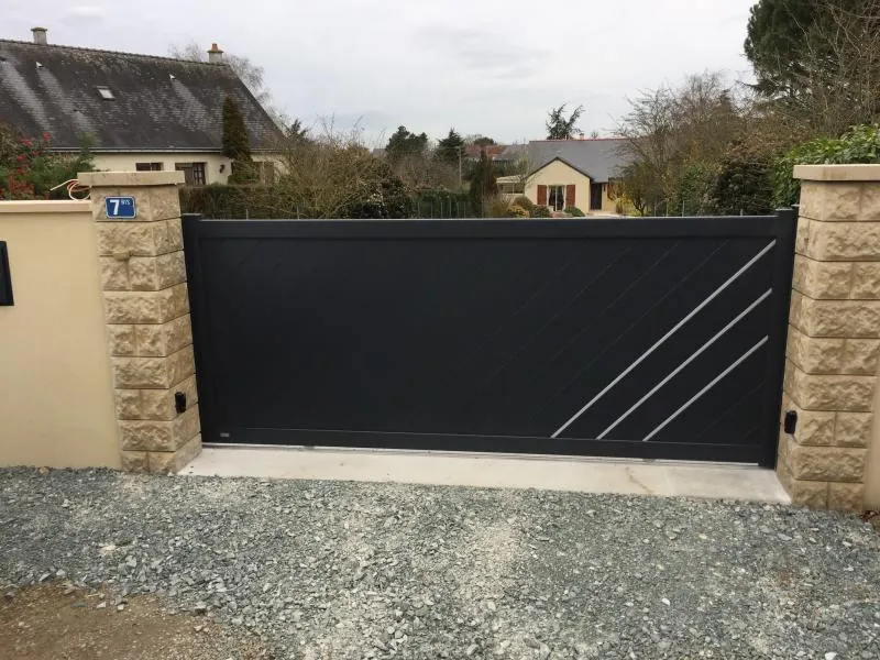Portail aluminium anthracite à lignes obliques installé devant une maison