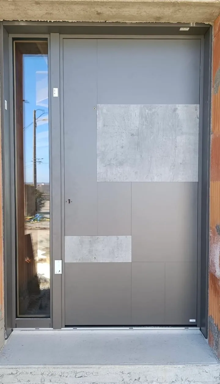 Porte d'entrée aluminium grise à effet béton posée sur une maison neuve