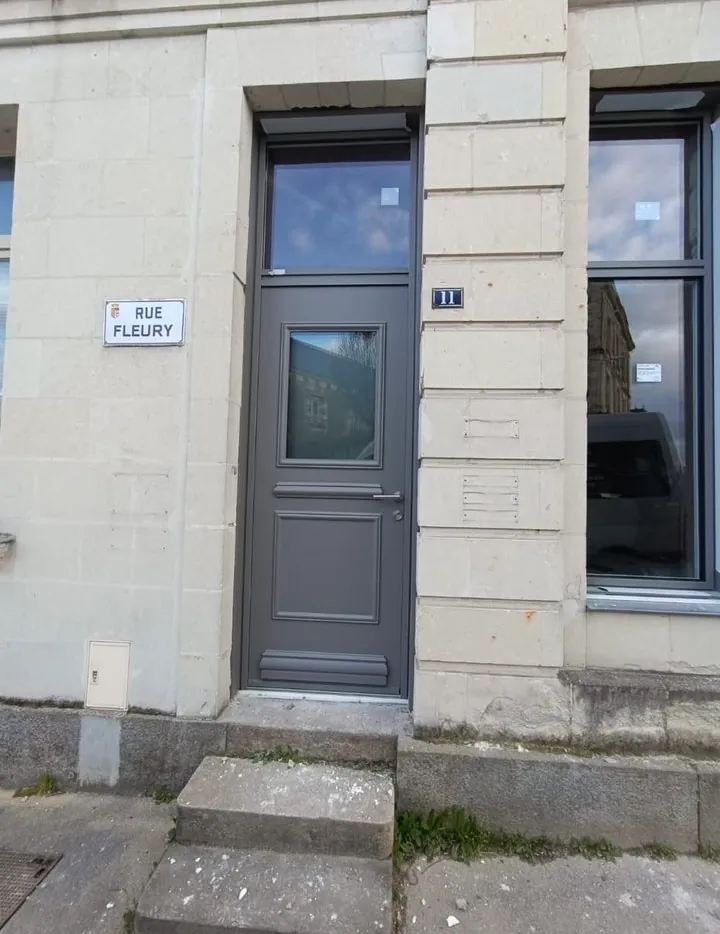 Porte d'entrée aluminium grise vitrée posée sur une façade en pierre de taille