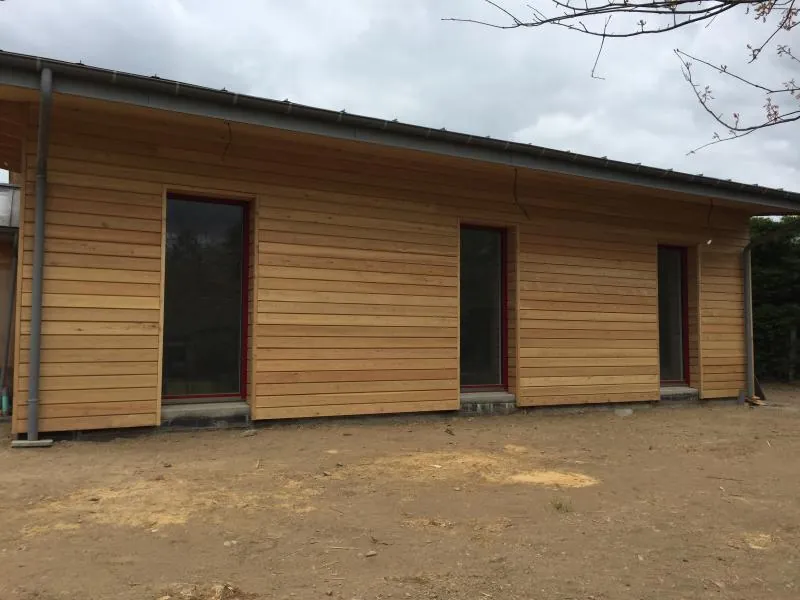 Façade en bardage bois clair d'une maison à ossature bois de plain-pied