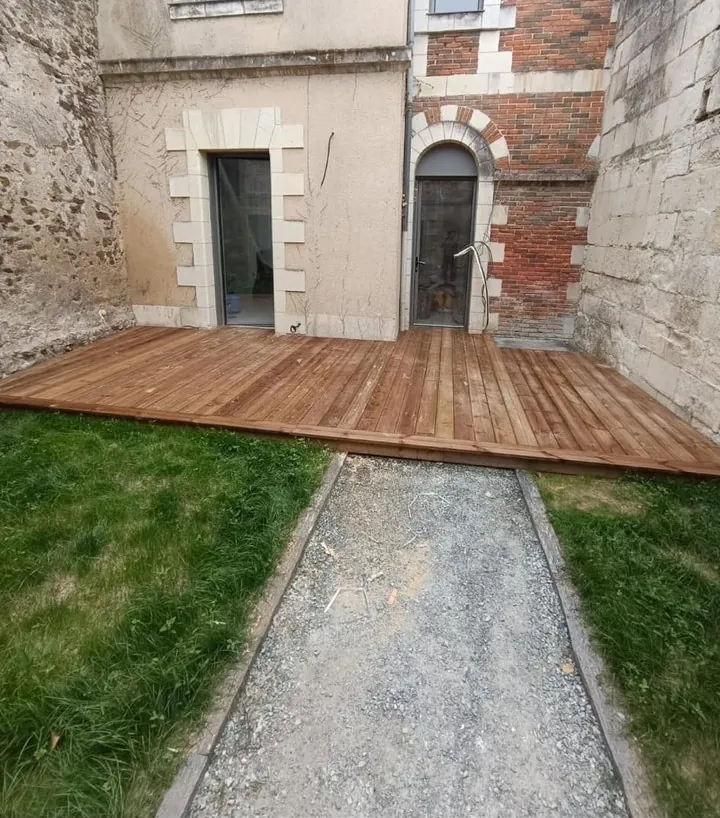 Terrasse en bois aménagée dans une cour intérieure entre bâtiments en pierre