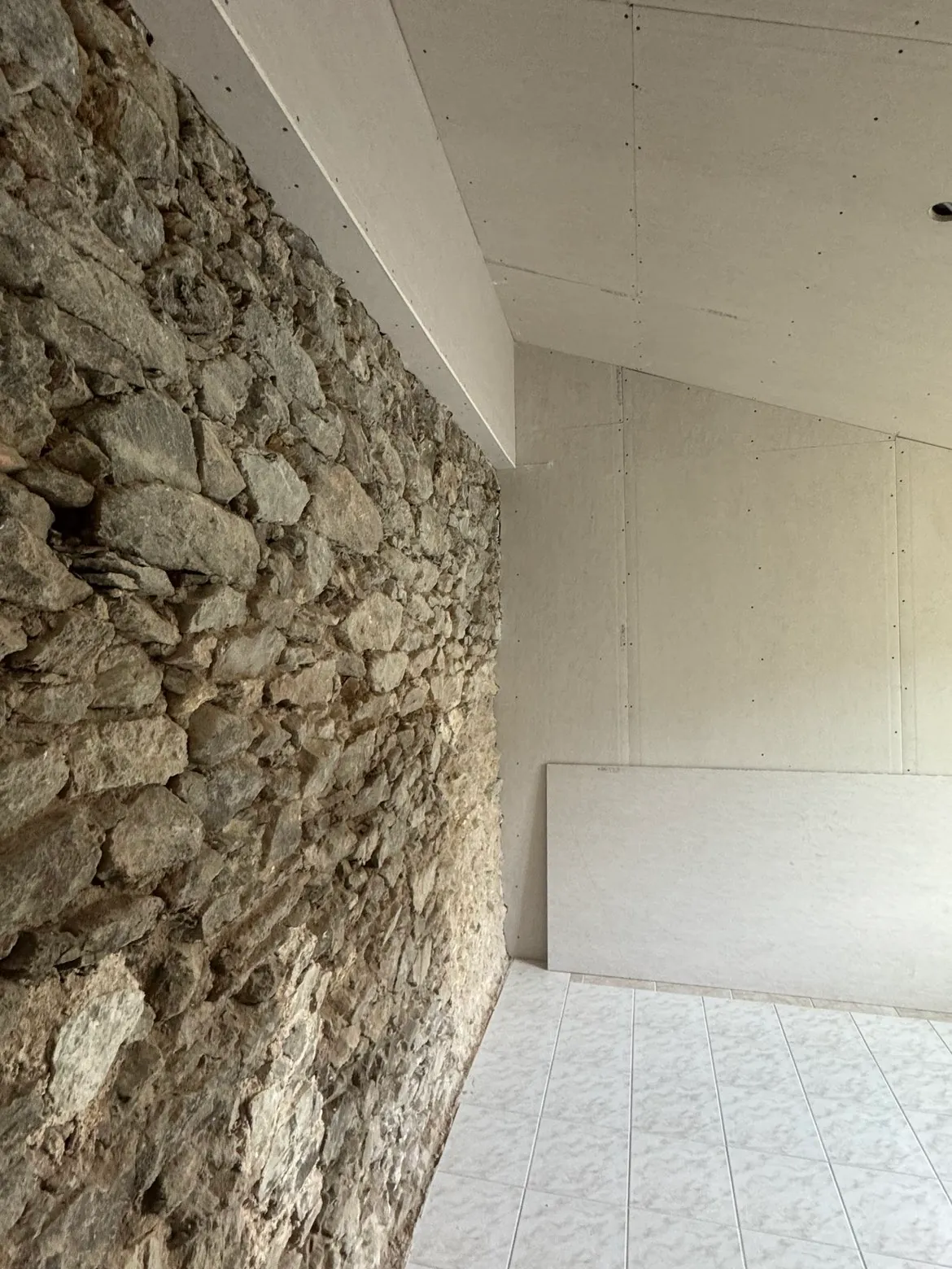 Détail de doublage et isolation contre un mur en pierre apparente